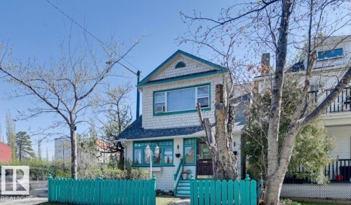 White shingle exterior with teal trim, featuring a gable roof and a wood entry door - 10649 125 Street Nw, Edmonton, AB 
