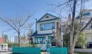White shingle exterior with teal trim, featuring a gable roof and a wood entry door - 10649 125 Street Nw, Edmonton, AB 