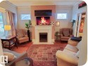 Central fireplace with a classic white mantel, wood-finish flooring, and multiple windows - 10649 125 Street Nw, Edmonton, AB 
