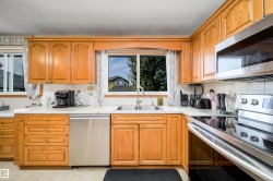 Wood-finish cabinetry, solid surface countertops, stainless steel appliances, and a double basin sink - 