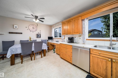 Kitchen featuring wood-finish cabinetry, stainless steel dishwasher, and a double basin sink - 4104 44 Street, Stony Plain, AB 