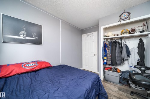 Wood-finish flooring, paneled interior door, and an open closet with built-in shelving and a clothing rod - 4104 44 Street, Stony Plain, AB 