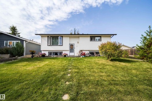 White siding exterior with dark trim accents, front yard with green lawn, and stepping stones - 4104 44 Street, Stony Plain, AB 