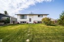 White siding exterior with dark trim accents, front yard with green lawn, and stepping stones - 4104 44 Street, Stony Plain, AB 