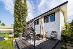 Expansive rear decking with dark wood-finish boards, white horizontal siding, and black trim windows - 