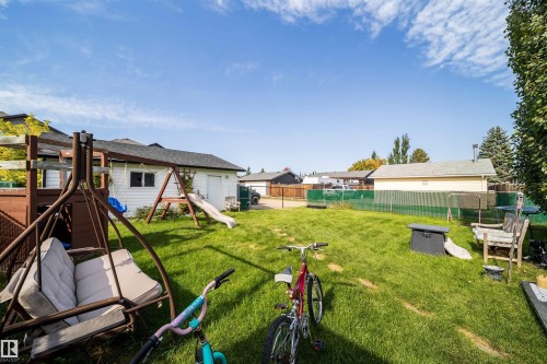 Expansive backyard featuring a lush lawn, privacy fencing, and a detached garage with a side-entry door - 4104 44 Street, Stony Plain, AB 