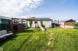 Expansive grassy yard with a white shed, a chain-link fence, and a wooden fence - 