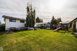 Expansive grassy yard with mature trees and a rear deck - 