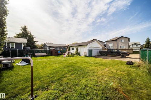 Expansive grass lawn with a chain-link fence, detached garage, and concrete parking pad - 4104 44 Street, Stony Plain, AB 