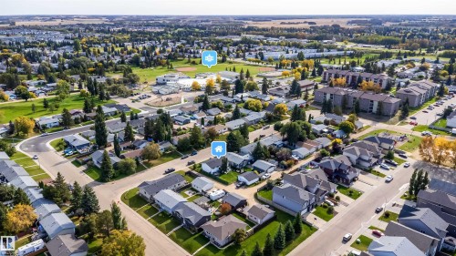 Aerial perspective showcasing a residential neighborhood with detached homes, apartment buildings, and green spaces - 4104 44 Street, Stony Plain, AB 