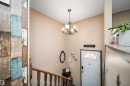 Decorative wall paneling, chandelier lighting, wood staircase railing, and a white entry door - 4104 44 Street, Stony Plain, AB 