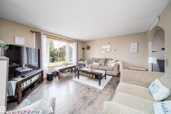 Spacious living area featuring wood-finish flooring, a large picture window, and an arched doorway - 