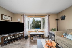 Living area featuring wood-finish flooring, neutral wall tones, and a large window with white trim - 