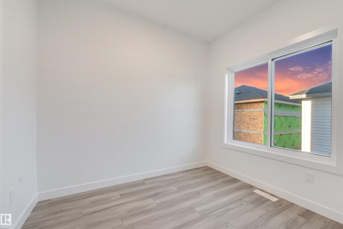 Bright interior with wood-finish flooring, white walls, and a large window - 1515 211 Street Nw, Edmonton, AB 