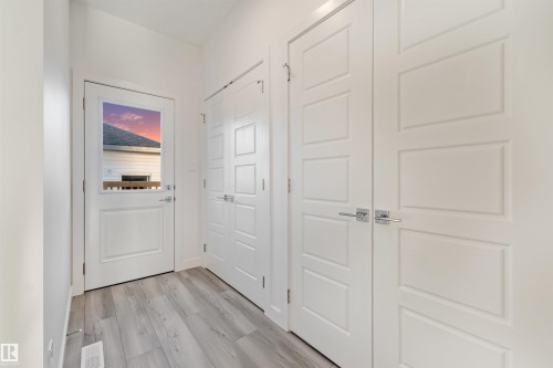 Entryway featuring light wood-finish flooring, white paneled doors with chrome hardware, and a glass-paneled exterior door - 1515 211 Street Nw, Edmonton, AB 