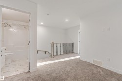 Plush carpeting, recessed lighting, and a modern stair railing with black spindles - 