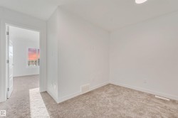 White painted walls, neutral-toned carpet, and a white interior door - 