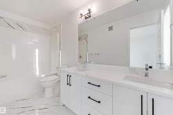 White vanity with dual integrated sinks, chrome faucets, and matte black hardware - 