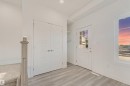 White interior door with glass panes, light wood-finish flooring, white walls, and a window with a scenic backdrop - 1515 211 Street Nw, Edmonton, AB 