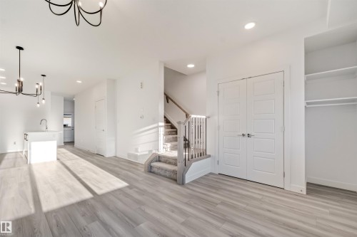 Open-concept living area featuring wood-finish flooring, recessed lighting, and a contemporary chandelier - 1515 211 Street Nw, Edmonton, AB 