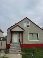 Stucco exterior with contrasting trim, gable roofline, and visible chimney - 