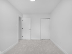Neutral-toned carpet flooring and white painted walls, featuring a flush mount ceiling light - 