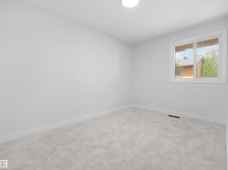 Recessed ceiling lighting, light gray carpeting, white walls, and a large window with white trim - 