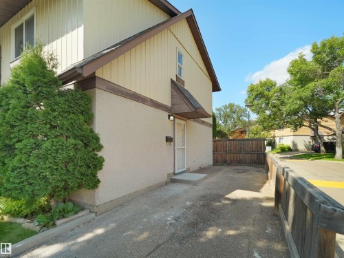 Exterior featuring vertical siding and stucco finishes, an asphalt driveway, and a wood privacy fence - 126 Woodstock Nw, Edmonton, AB 