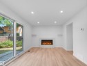 Recessed lighting, wood-finish flooring, white walls, built-in electric fireplace, and sliding glass patio doors - 126 Woodstock Nw, Edmonton, AB 