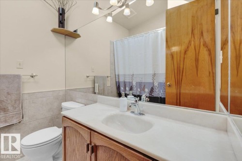 Vanity with white countertop, wood-finish cabinetry, and chrome fixtures - 15012 77 Avenue Nw, Edmonton, AB 