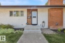 Exterior featuring a white entry door with decorative glass, cedar shake siding accents, and a brick chimney - 15012 77 Avenue Nw, Edmonton, AB 