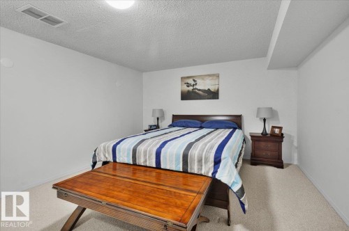 Wall-to-wall carpeting with light-toned walls and a textured ceiling - 15012 77 Avenue Nw, Edmonton, AB 