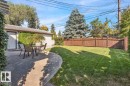 Expansive concrete patio with a manicured lawn, established landscaping, and a privacy fence - 15012 77 Avenue Nw, Edmonton, AB 