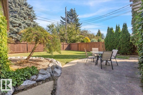 Patio with concrete surface, rock garden bed, manicured lawn, and wood privacy fencing - 15012 77 Avenue Nw, Edmonton, AB 
