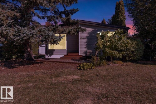 Siding exterior with multiple windows, a front porch, and mature trees - 15012 77 Avenue Nw, Edmonton, AB 