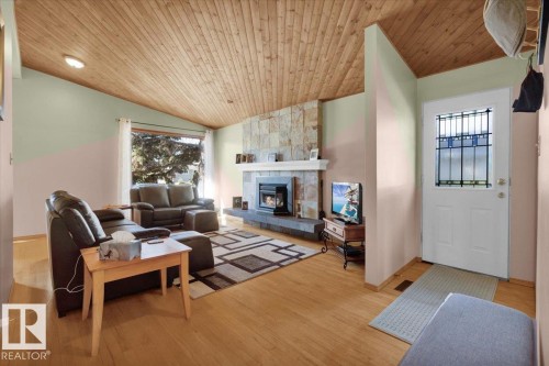 Vaulted wood-finish ceiling, hardwood flooring, stone-clad fireplace, and a front entry door with decorative glass inserts - 15012 77 Avenue Nw, Edmonton, AB 