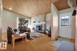 Vaulted wood-finish ceiling, hardwood flooring, stone-clad fireplace, and a front entry door with decorative glass inserts - 
