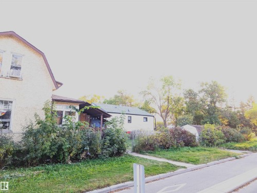 Exterior with stucco finish, covered porch, and mature landscaping - 9115 119 Avenue Nw, Edmonton, AB 