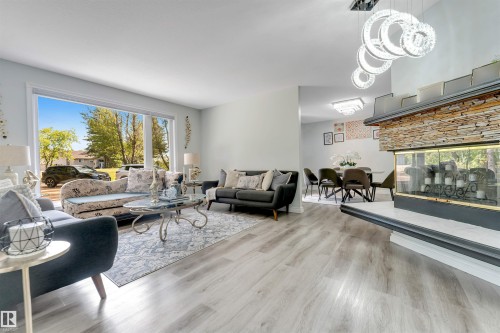Living area featuring a stone-clad fireplace, wood-finish flooring, and large window - #37 23020 Township Road 522 Rd, Rural Strathcona County, AB 