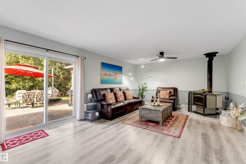 Sliding glass door, wood-finish flooring, half-wall paneling, ceiling fan, and freestanding stove - #37 23020 Township Road 522 Rd, Rural Strathcona County, AB 
