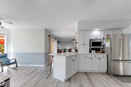 Modern kitchen featuring white cabinetry, stainless steel refrigerator, built-in microwave, and light-toned countertops - #37 23020 Township Road 522 Rd, Rural Strathcona County, AB 