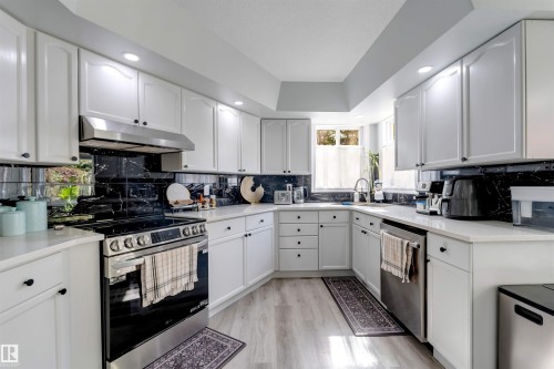 White cabinetry, black-finish backsplash, stainless steel appliances, light-finish flooring, and recessed lighting - #37 23020 Township Road 522 Rd, Rural Strathcona County, AB 