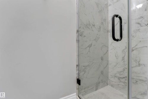 Shower enclosure featuring glass panels, a matte black pull handle, and marble-look wall tiling - #37 23020 Township Road 522 Rd, Rural Strathcona County, AB 