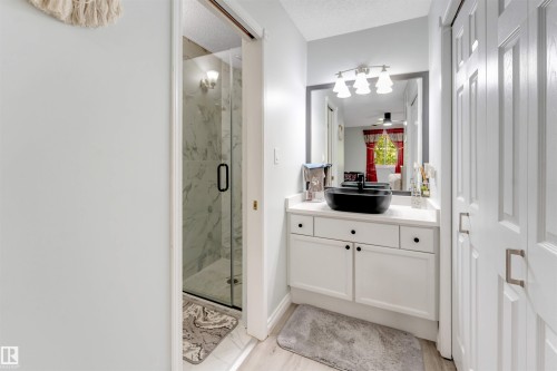 Glass-enclosed shower with marble-finish wall tile, white vanity with black vessel sink, and paneled doors - #37 23020 Township Road 522 Rd, Rural Strathcona County, AB 