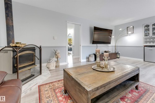 Wood-burning stove with a stone hearth, wood-finish flooring, and two-tone wall treatment - #37 23020 Township Road 522 Rd, Rural Strathcona County, AB 