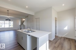 Kitchen island with a double basin sink, light-toned countertops, and recessed lighting - 