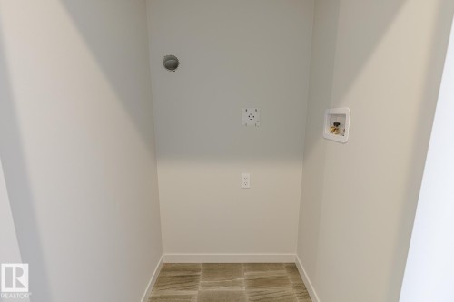 Utility space featuring tiled flooring, a wall-mounted dryer vent, and plumbing hookups - 3611 Triomphe Boulevard, Beaumont, AB 