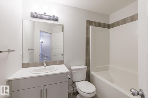 White vanity with an integrated sink and chrome faucet - 3611 Triomphe Boulevard, Beaumont, AB 