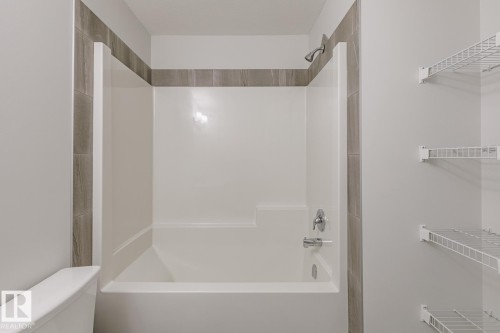 White shower/tub combination with chrome fixtures and gray tile surround - 3611 Triomphe Boulevard, Beaumont, AB 