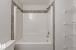 White shower/tub combination with chrome fixtures and gray tile surround - 
